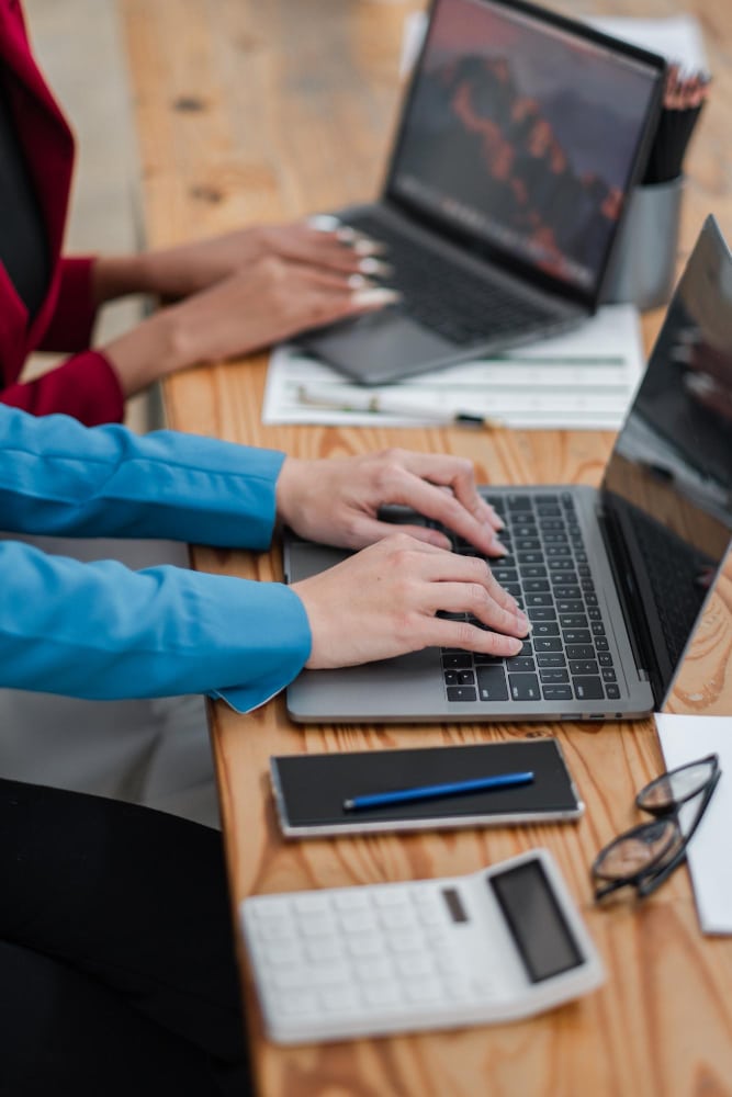 Professionals working on laptops at a desk supported by laptop hire